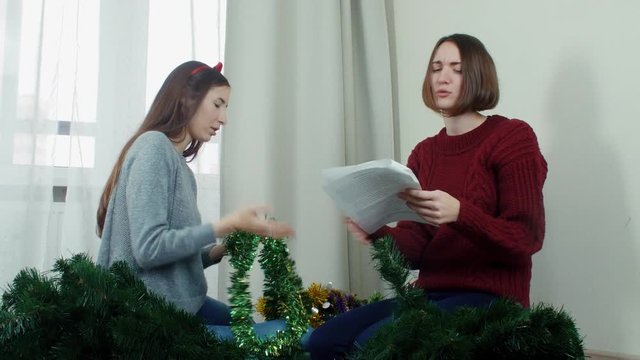 Two young girl preparing Christmas tree for decorations and having fun New year
