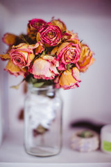 Bouquet of dry pink and yellow roses stands in the bottle