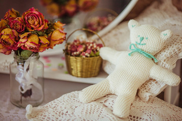 White knitted bear with mint bow lies on white pillows