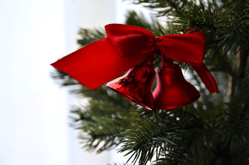 Close up of Fir tree branch and traditional large glitter red bells and bow. Christmas or New Year concept. Winter festive background. Copy space.