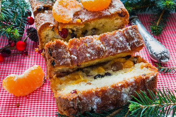 Homemade Christmas fruit sweet cake cooked with tangerines, raisins and dried cranberry, Xmas decoration on table