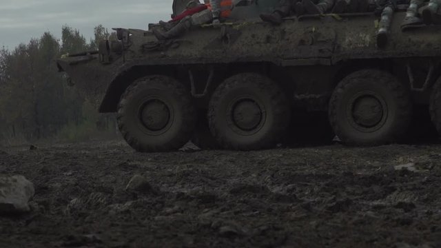 Military armored personnel carrier travels along the muddy road. Dirty armored vehicle