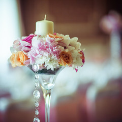 Thick white candle stands in the pretty pink bouquet