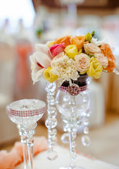 Crystal vase with pink and yellow bouquet stands on the table