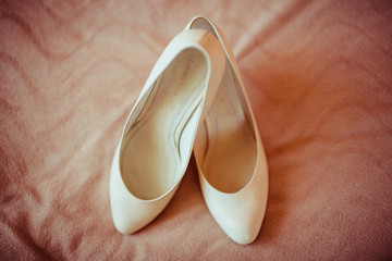 Classy white shoes stand on the peach carpet