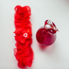 Bride's red garter lies behind a bottle of parfume