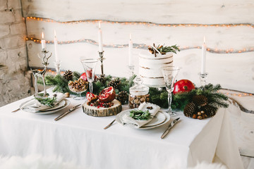A neat and cozy table for two in christmas decorations, wooden wall with yellow lights on the background