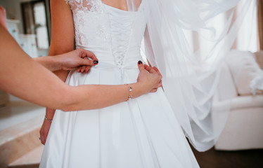 Obraz na płótnie Canvas Woman with black nails adjusts a bow on bride's dress