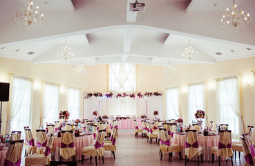 Chairs in beig cloth with violer ribbons stand in white restaura