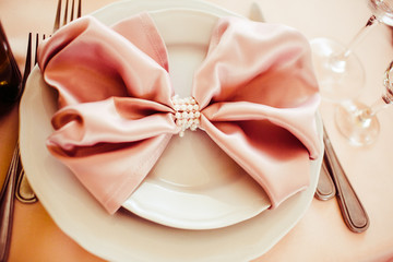 Serviette in the form of bow lies on the white plate
