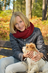 Reifere Frau mit Terrier genießt den Herbst