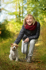 Attraktive reifere Frau mit Terrier im Wald