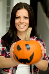 Attractive woman at home with a halloween pumpkin