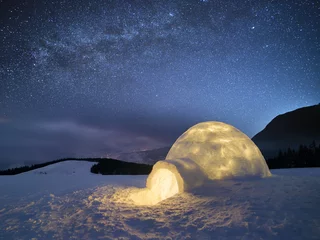 Fotobehang Winternachtlandschap met een sneeuwiglo en een sterrenhemel © Oleksandr Kotenko
