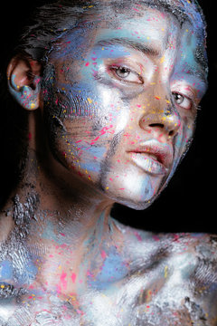 Portrait of a woman with colorful paint brushstroken on face. Bright blue eyes. Advertising Space