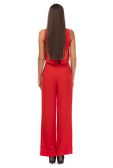 Back view. Young brunette woman in red pantsuit