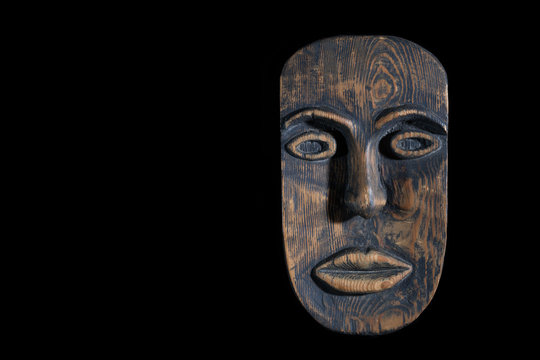 the mask is made of wood isolated on black background. free space for text