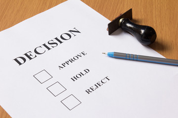 Decision paper (approve, hold, reject) with pen, rubber stamp