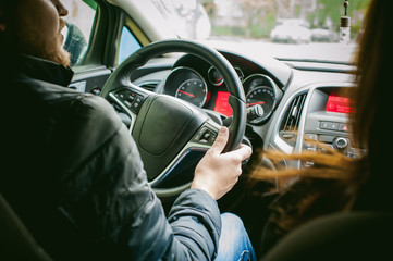 man drives a car. A guy in a jacket sits behind the wheel of a car traveling on the road in a traffic jam. Photo taken off the seat, due to the driver's back