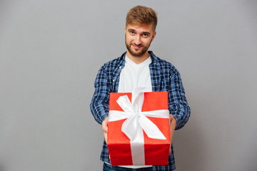 Portrait of a happy man giving gift box on camera