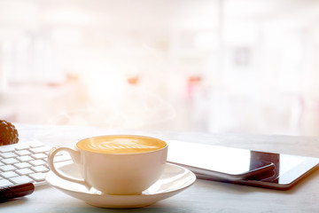 Business Office scene, digital tablet and smartphone with Latte art coffee with morning light.