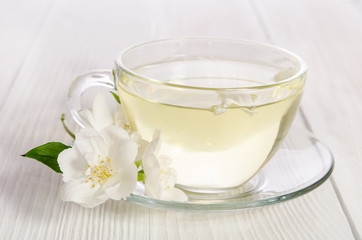 Obraz na płótnie Canvas Glass cup of tea with jasmine on the white wooden background