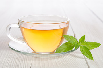 Glass cup of tea with mint on the white wooden table