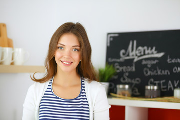 Young woman standing near desk in the kitchen