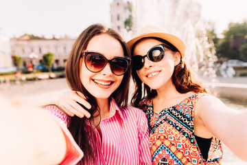 two pretty fresh hipster young brunette and blonde best friends girls,make selfie and having fun.