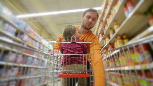 Smiling father and daughter chooses products in the supermarket, man buys drinks in store