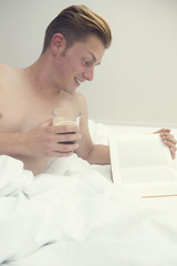 blond man in bed reading a book