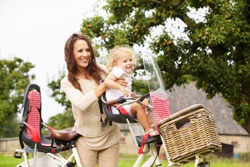 Young woman with her daughter on bicycle in the park