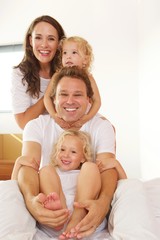 Cheerful young family in bed at home