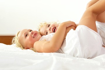 Beautiful little girls lying together on bed