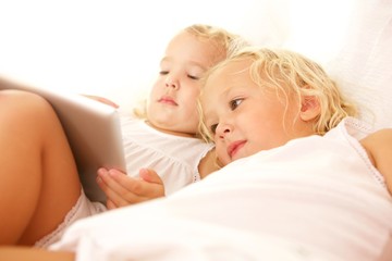 Obraz na płótnie Canvas Children using digital tablet on bed