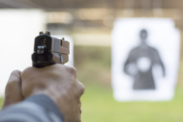 Man Firing Pistol at Target in Shooting Range - 124133656