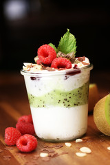 Colorful fruit salad with cream and chocolate in a jar on rustic wooden background