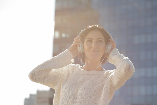 Woman listen music at building background, low contrast image