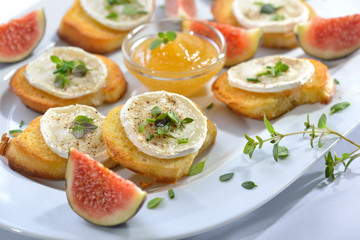 Gebackene Crostini-Partyhäppchen mit Ziegenkäse, frischen Kräutern und Feigenhonig serviert - Baked spicy crostini appetizers with goat cheese and fresh herbs served with fig honey