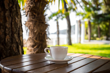Cup with .coffee on table over sea landscape with sunlight. Beauty nature background