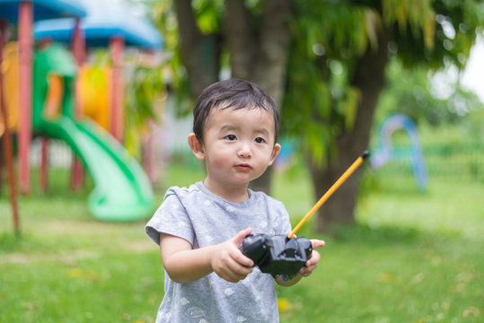 Little Asian kid holding a radio remote control (controlling han