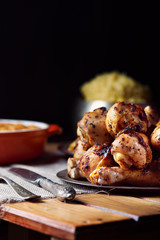 Close view of grilled chicken legs, knife, and fork mash potatoes on a table on a black background. Dark photo. Vertical shot