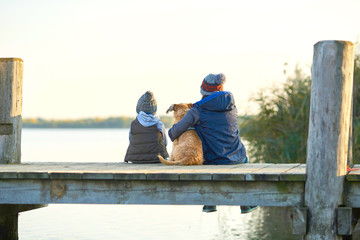 Vertrauen - zwei Br&uuml;der sitzen mit Hund am Steg