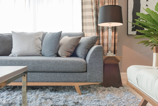 row of pillows on grey sofa with black lamp in living room