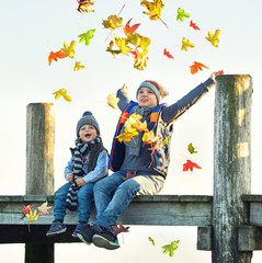 Kinder werfen buntes Laub in die Luft, Herbsttag am See