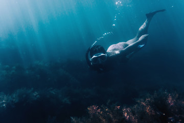 Female free diver swimming among seaweed