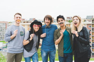 Knee figure of group of young multiethnic friends posing using masks in shape of object - funny, happiness, having fun concept