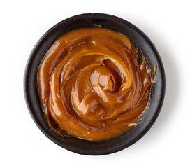 Caramel sauce  in round dish isolated on white background