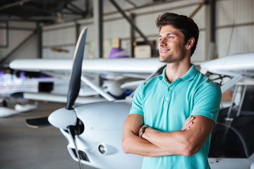 Man standing with arms crossed near small airplane