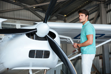 Man pilot standing near small private airplane © Drobot Dean